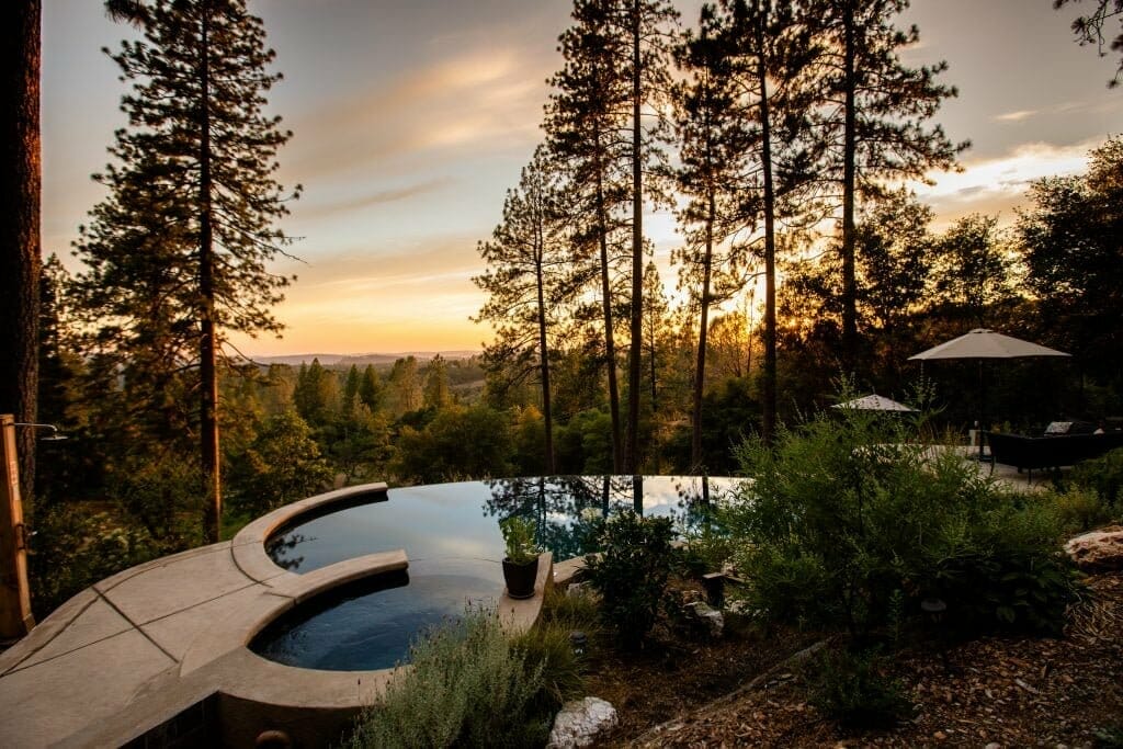 the sunset view from the outdoor pool in the middle of the woods